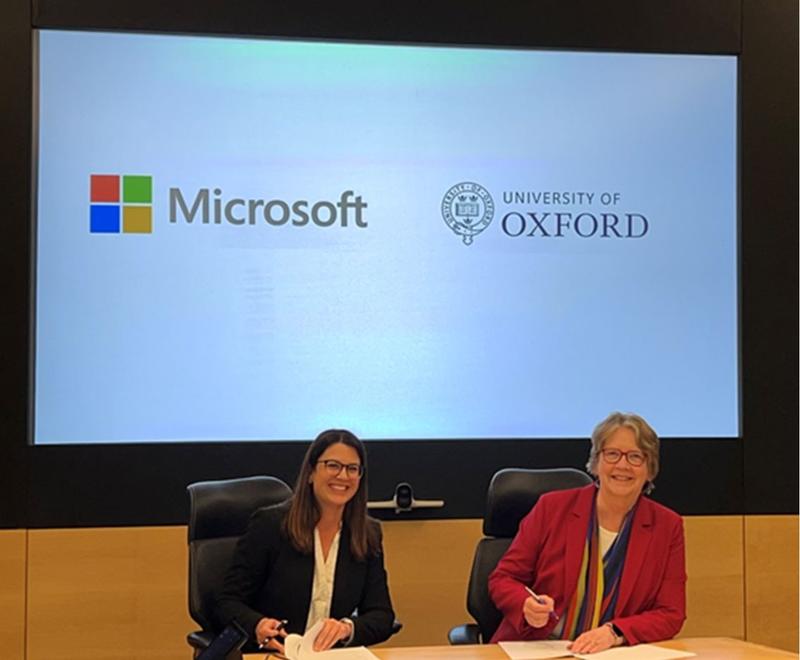 Anne Trefethen and another women from Microsoft posing for the camera as they sign an agreement