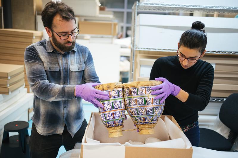 Two people carefully packing a drum into storage box