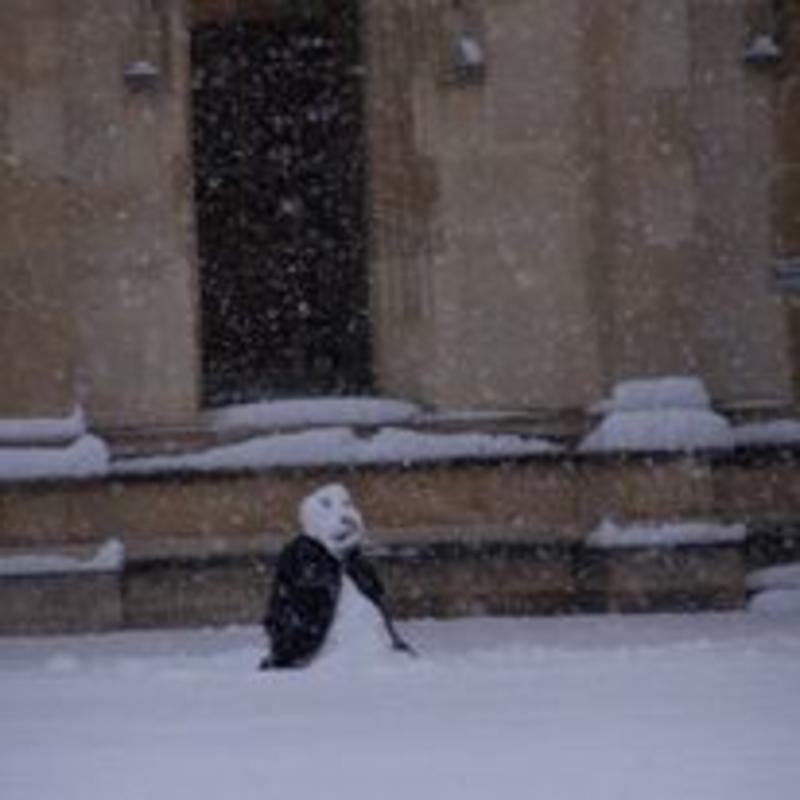 a snowperson with a black gown outside in the snow