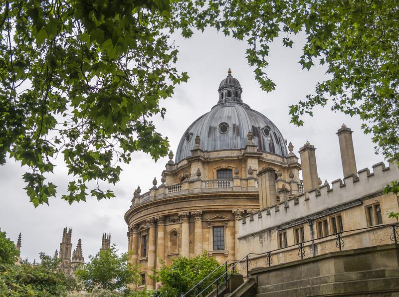 the domed building of Oxford's Radcliffe Camera visible through green leaves of trees