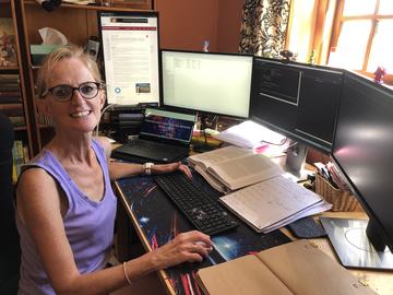 Sarah Bauermeister's home office Sarah sat at a desk in her home with four computer screens