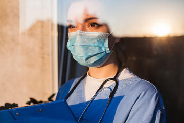 A female doctor in PPE looking out of the window