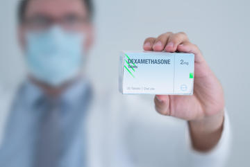 Doctor in a mask holding a box of dexamethasone 