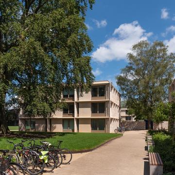 One of the Master's Field accommodation building set behind a paved entrance way with trees and bikes